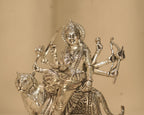 Close view of the silver Durga figure, her crown, her jewellery and the weapons in her eight hands.