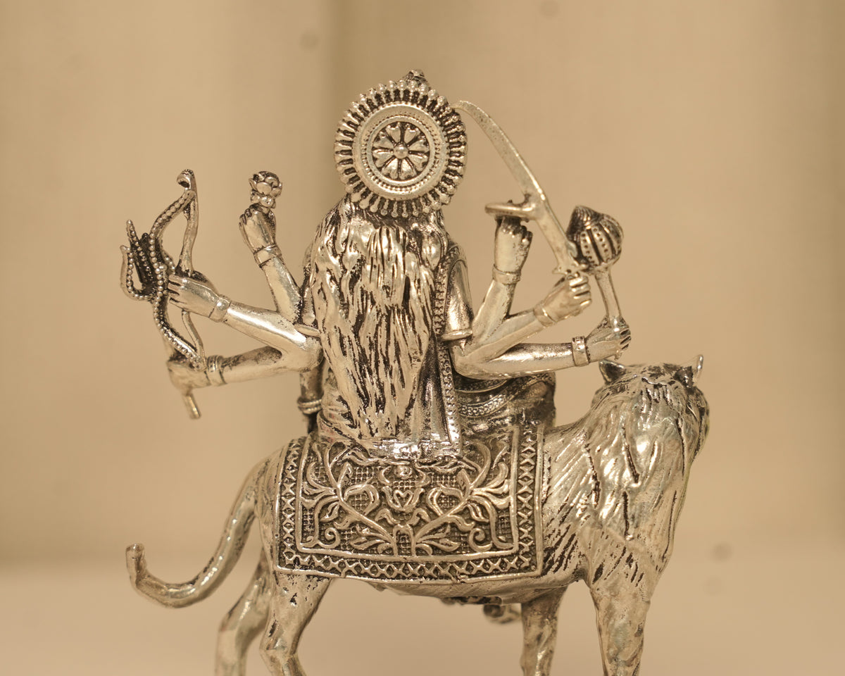 Close view of the back of the silver Durga idol, showing the disc and the cut work on the saddle cloth.