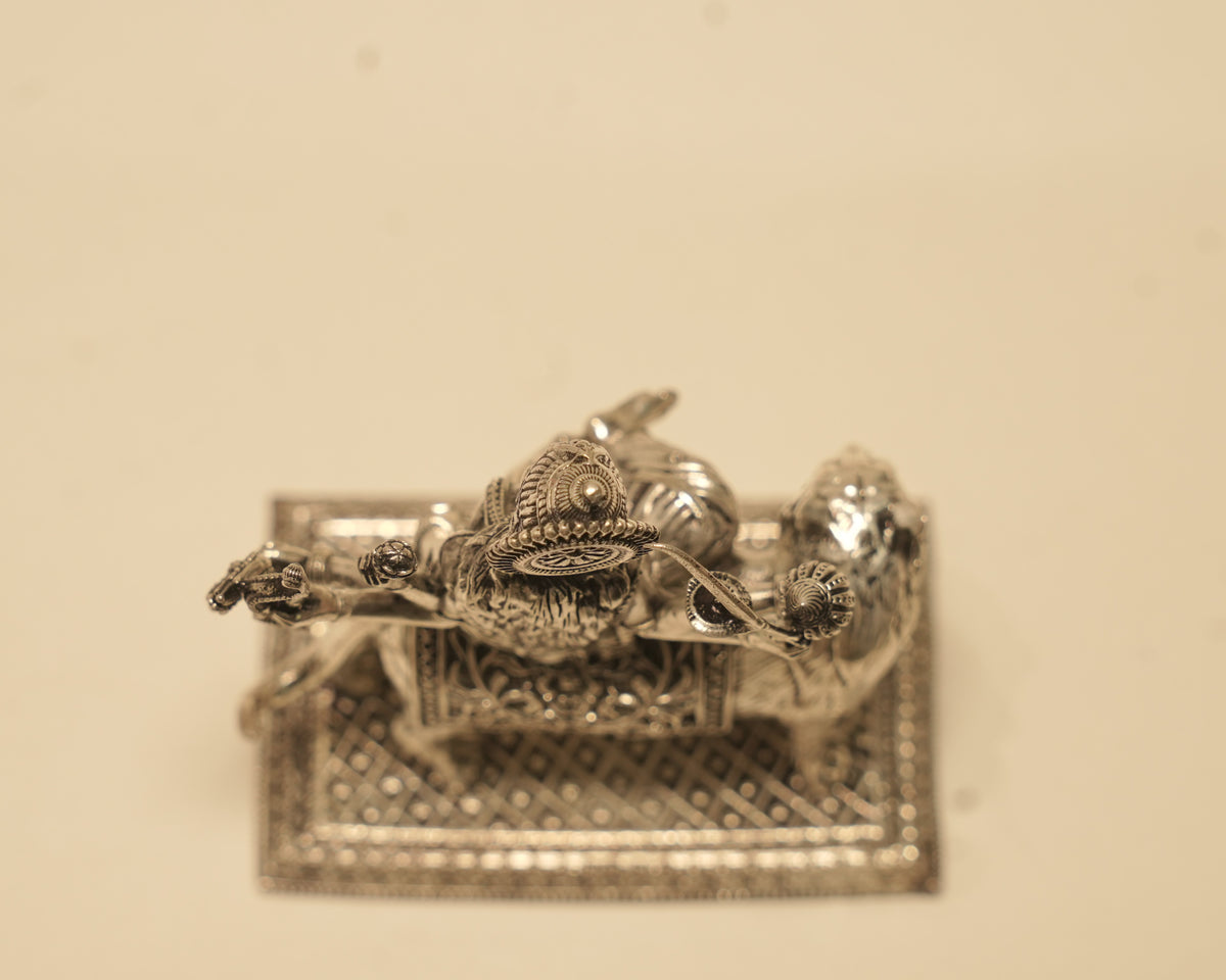 The silver Durga idol laid on its side, showing the pierced work along the edge of the base.