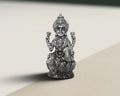 Antique finish sterling silver Lakshmi idol seated on a lotus base, lit against a pale background.