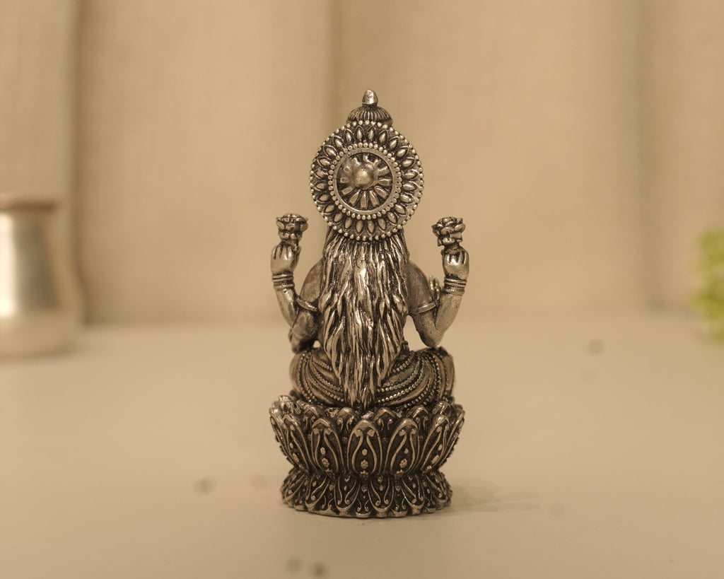 Back of the antique silver Lakshmi idol, showing the fluted disc behind her head and the lotus petals below.