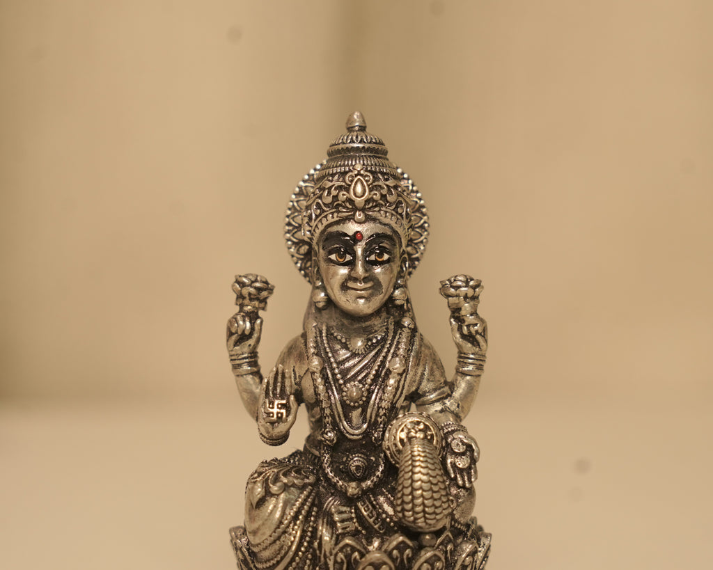 Close view of the antique silver Lakshmi figure, her crown, her necklaces and the swastik at her side.