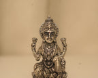 Close view of the antique silver Lakshmi figure, her crown, her necklaces and the swastik at her side.
