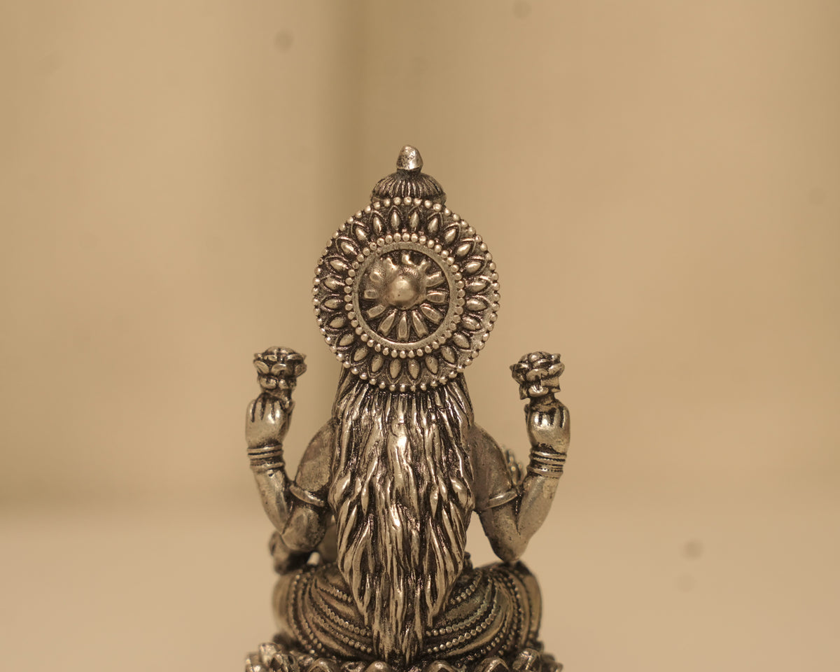 Close view of the back of the antique silver Lakshmi idol, showing the disc and the fall of the saree.