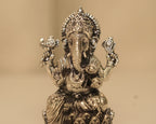 Close view of the antique silver Ganesh figure, the crown, the trunk and the objects in his four hands.