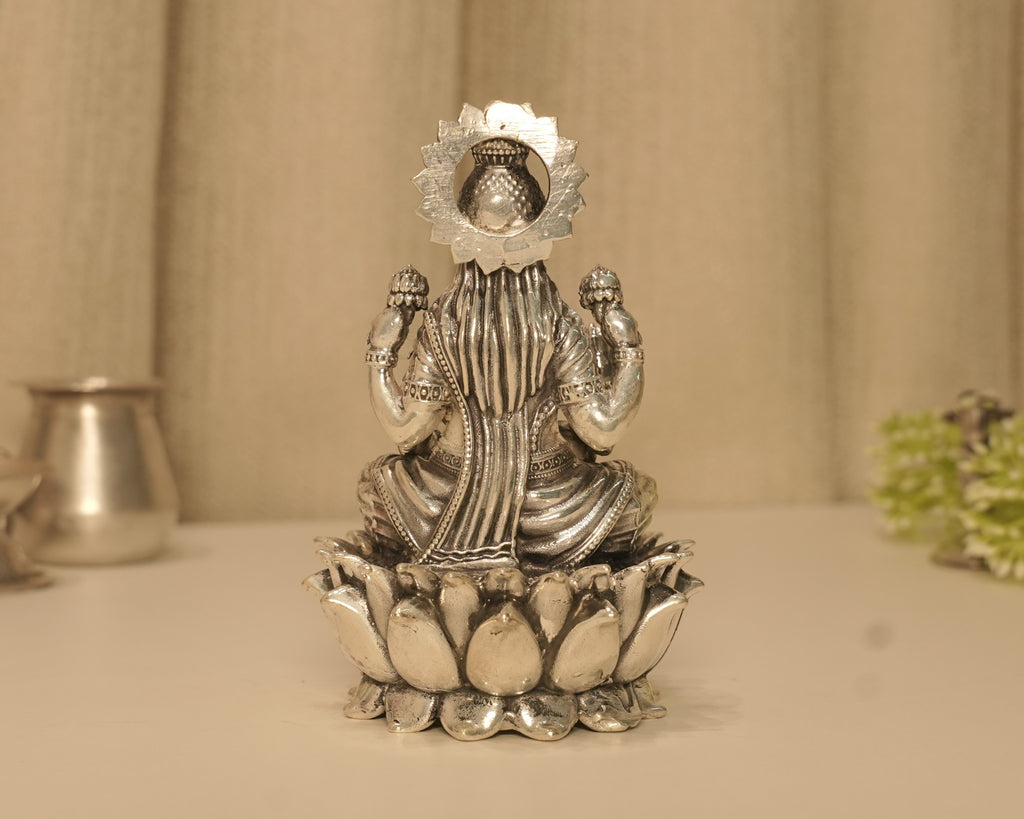 Back of the large silver Lakshmi idol, with a kalash showing through the opening in the arch.