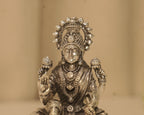Close view of the silver Lakshmi figure, her crown, her necklaces and the lotus buds in her hands.