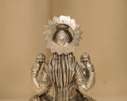 Close view of the back of the large silver Lakshmi idol, showing the kalash within the beaded arch.