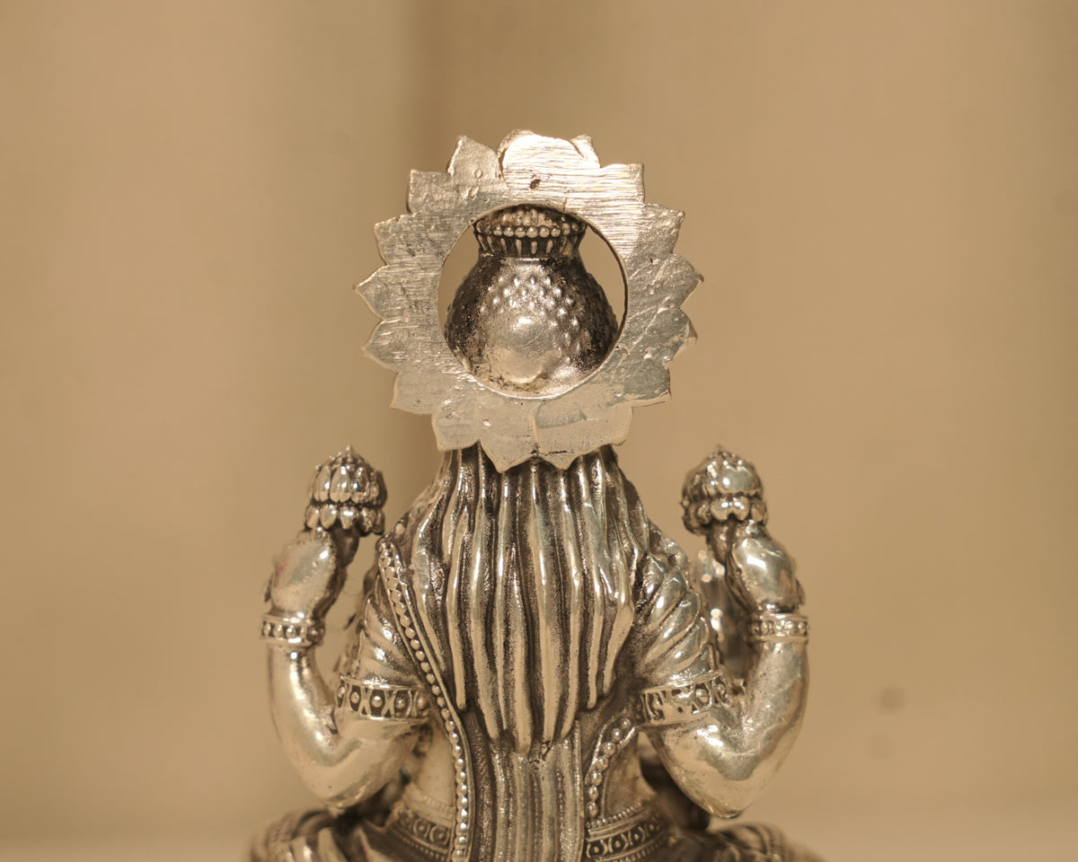 Close view of the back of the large silver Lakshmi idol, showing the kalash within the beaded arch.