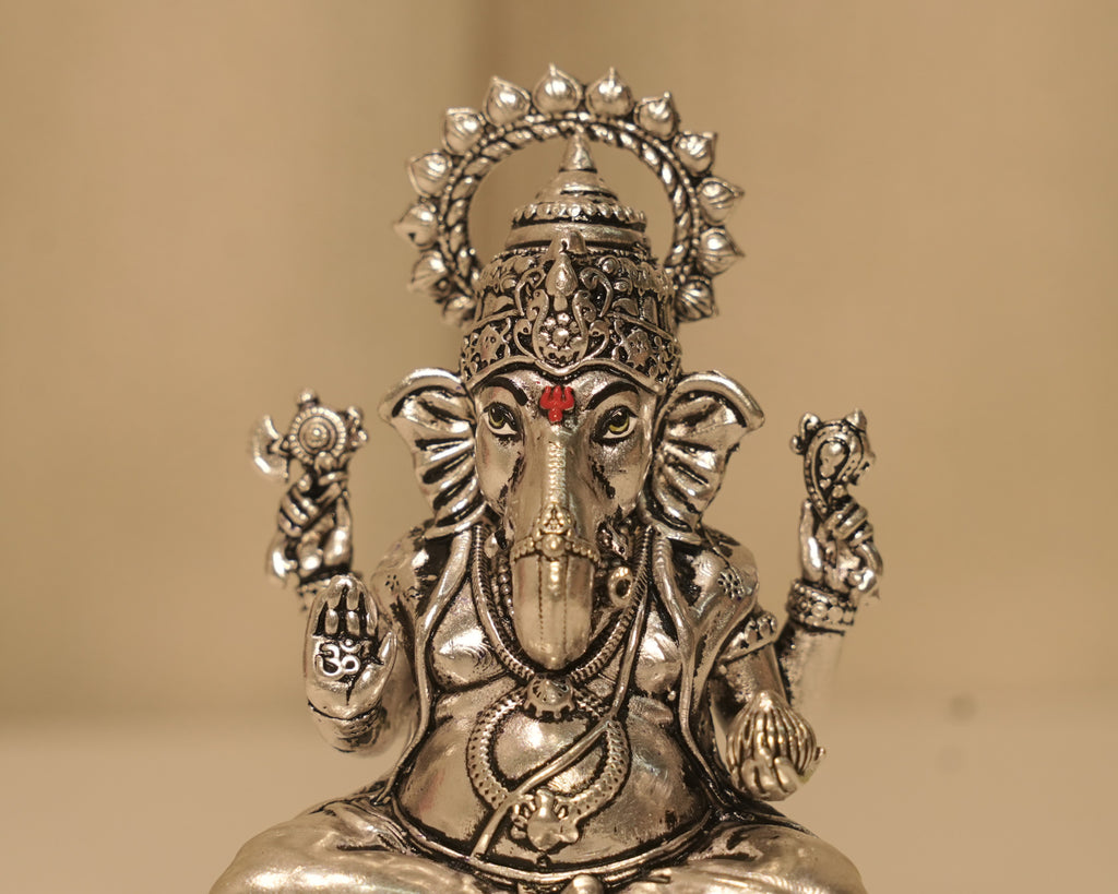 Close view of the silver Ganesh figure, the crown, the trunk and the Om marked on his palm.