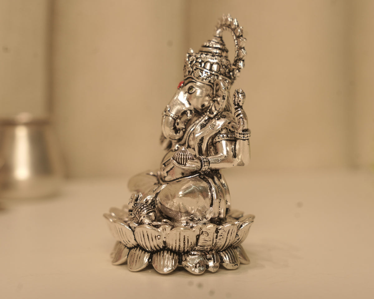 Side view of the large silver Ganesh idol, showing the crown and the lotus base in profile.