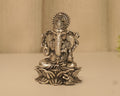 Antique finish sterling silver Ganesh idol with a tall crown, seated on a lotus base on a pale surface.