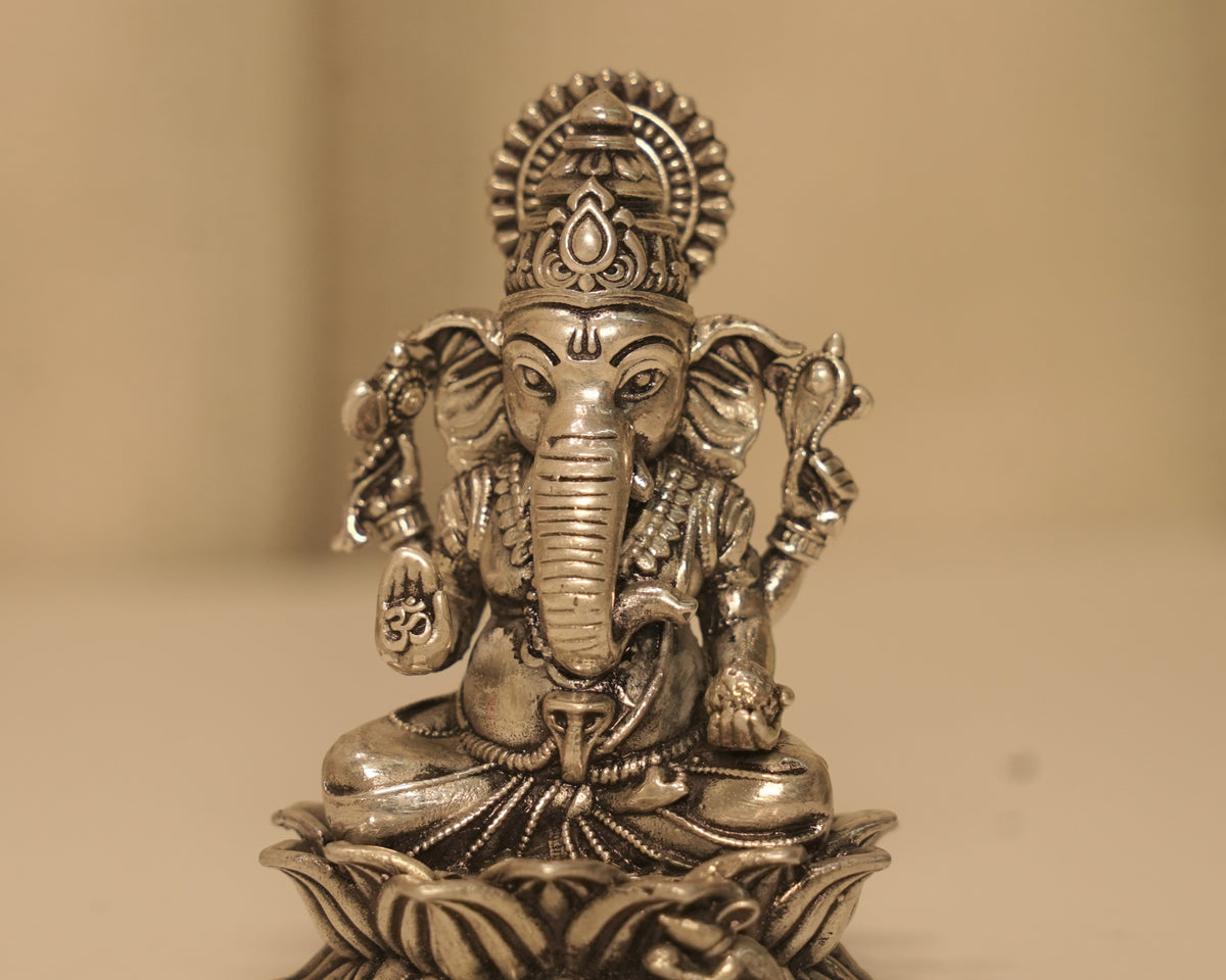 Close view of the antique silver Ganesh figure, the crown, the trunk and the Om marked on his palm.
