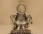 Close view of the back of the antique silver Ganesh idol and the round disc behind it.