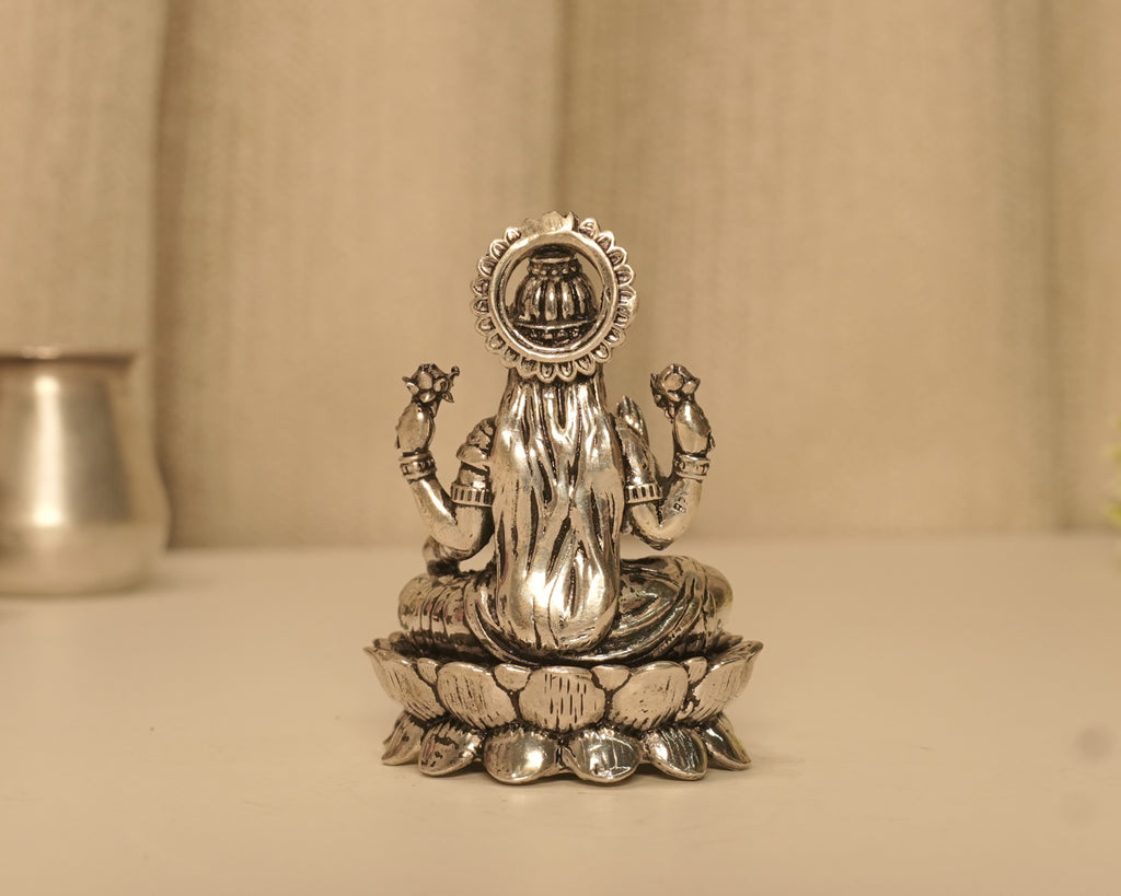 Back of the silver Lakshmi idol, with a kalash showing through the opening in the beaded arch.