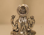 Close view of the back of the silver Lakshmi idol, showing the kalash set within the arch.