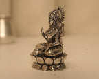 Side view of the silver Lakshmi idol, showing the crown and the lotus base in profile.