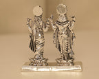Back of the silver Vishnu and Lakshmi figures, showing the rayed crowns and the plain bright plinth.