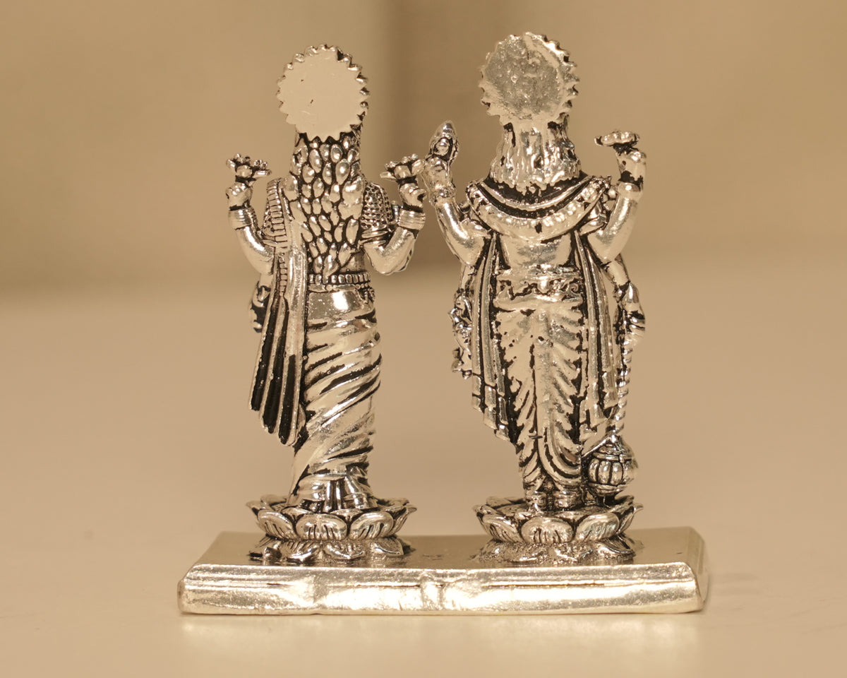 Back of the silver Vishnu and Lakshmi figures, showing the rayed crowns and the plain bright plinth.