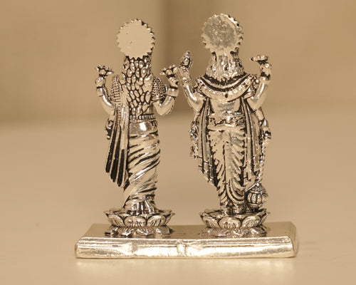 Back of the silver Vishnu and Lakshmi figures, showing the rayed crowns and the plain bright plinth.