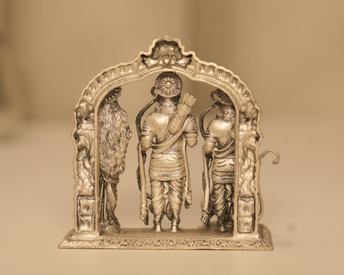 Close view of the three antique silver figures standing within the carved arch.