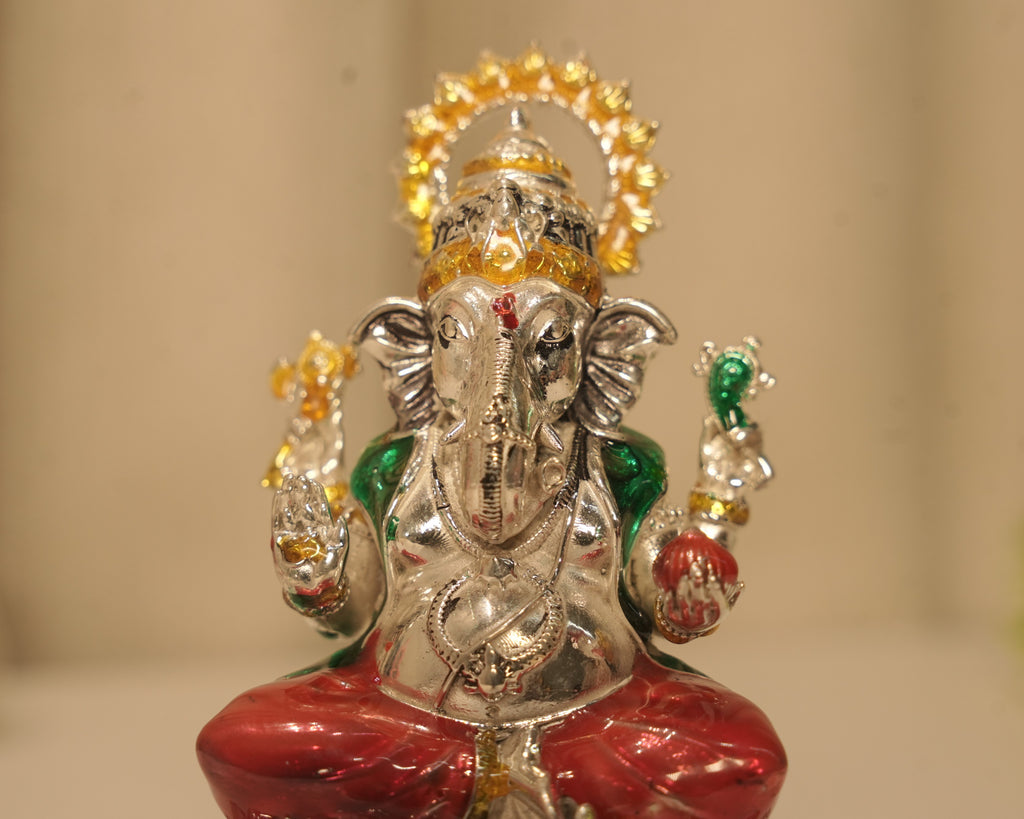 Close view of the enamelled silver Ganesh figure, the gold enamel crown and the red and green robes.