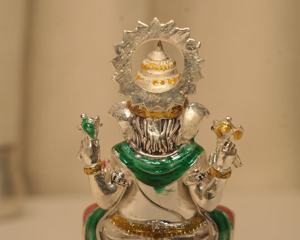 Close view of the back of the enamelled silver Ganesh idol and the rayed disc behind the crown.