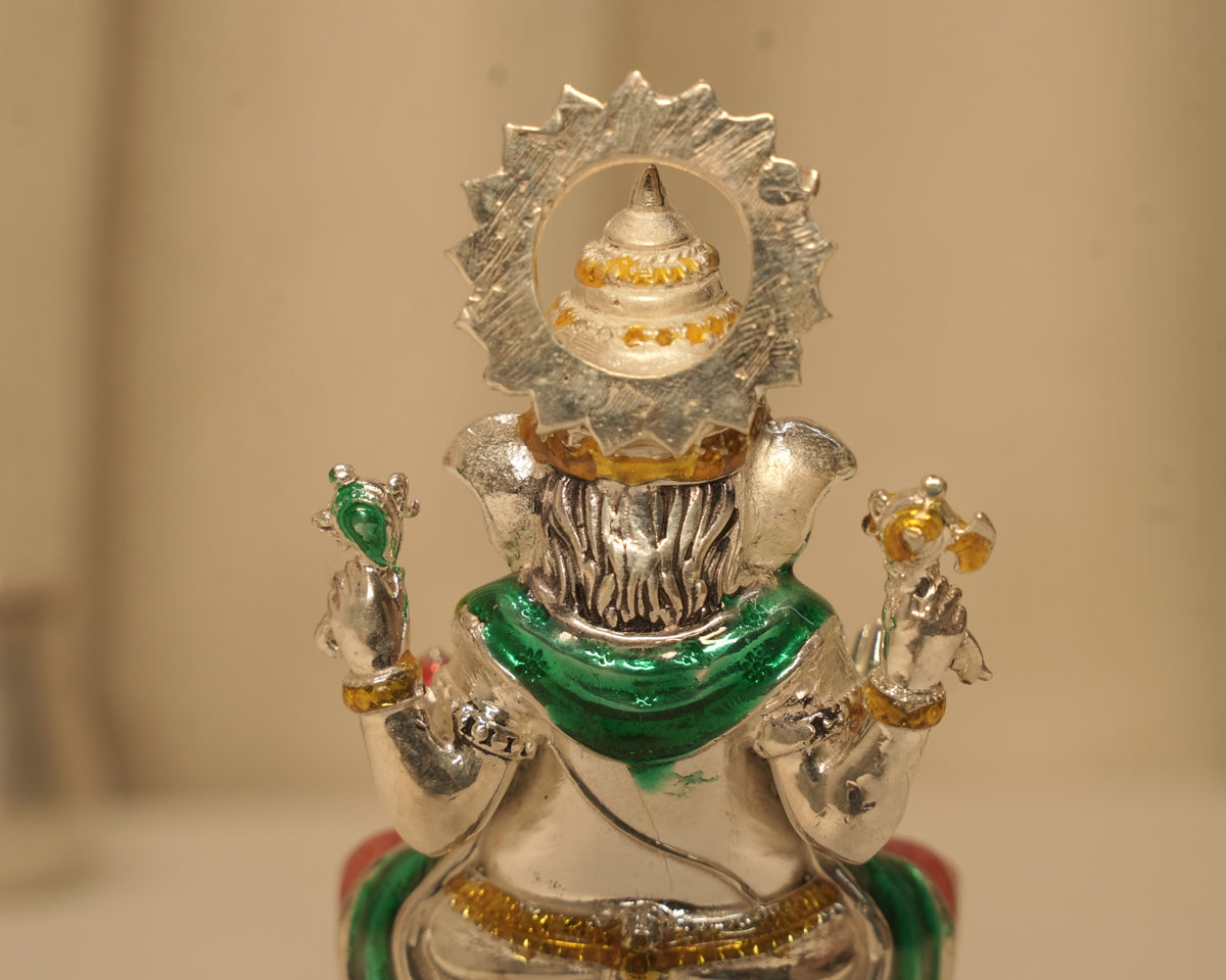 Close view of the back of the enamelled silver Ganesh idol and the rayed disc behind the crown.