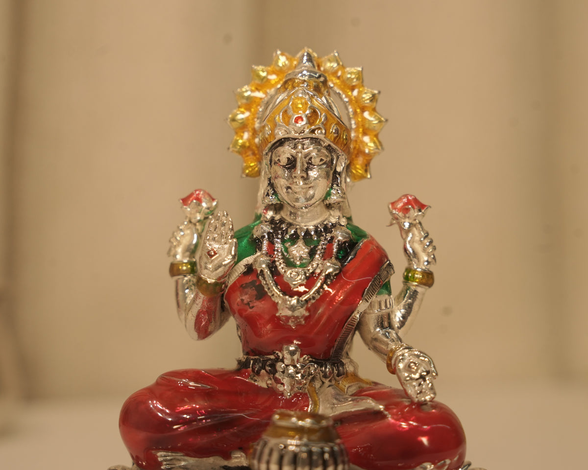 Close view of the enamelled silver Lakshmi figure, the gold enamel crown and the red and green robes.