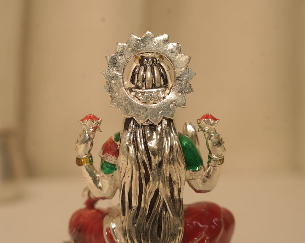 Close view of the back of the enamelled silver Lakshmi idol and the disc behind the crown.