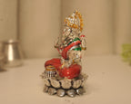 Side view of the enamelled silver Lakshmi idol, showing the lotus base and the pot at her knee.