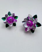 The large and small silver and pink enamel lotus flowers side by side on a white surface.