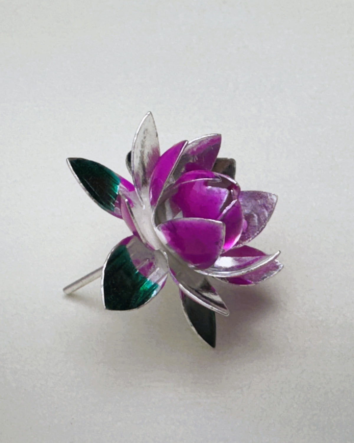 Side view of the silver lotus, showing the stem and the green enamel leaves underneath.