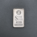 5 gram fine silver bar, front face stamped Fine Silver 999.0 and 5 grams, on a dark grey surface.