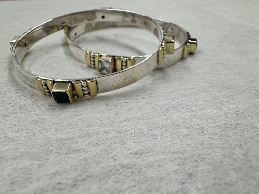 Sterling silver bangles photographed at eye level, showing how far the gold-tone bezels stand above the band.