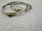 Sterling silver bangles photographed at eye level, showing how far the gold-tone bezels stand above the band.