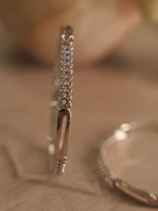 Sterling silver bangle standing upright, showing twin rows of American Diamond and a rose-tone oblong station.