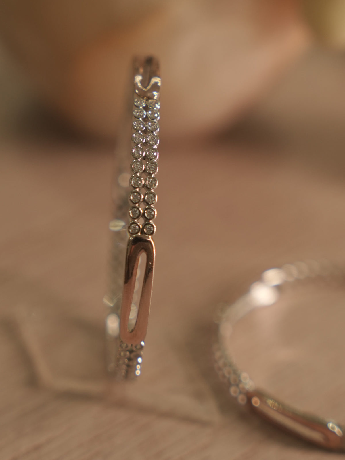 Sterling silver bangle standing upright, showing twin rows of American Diamond and a rose-tone oblong station.