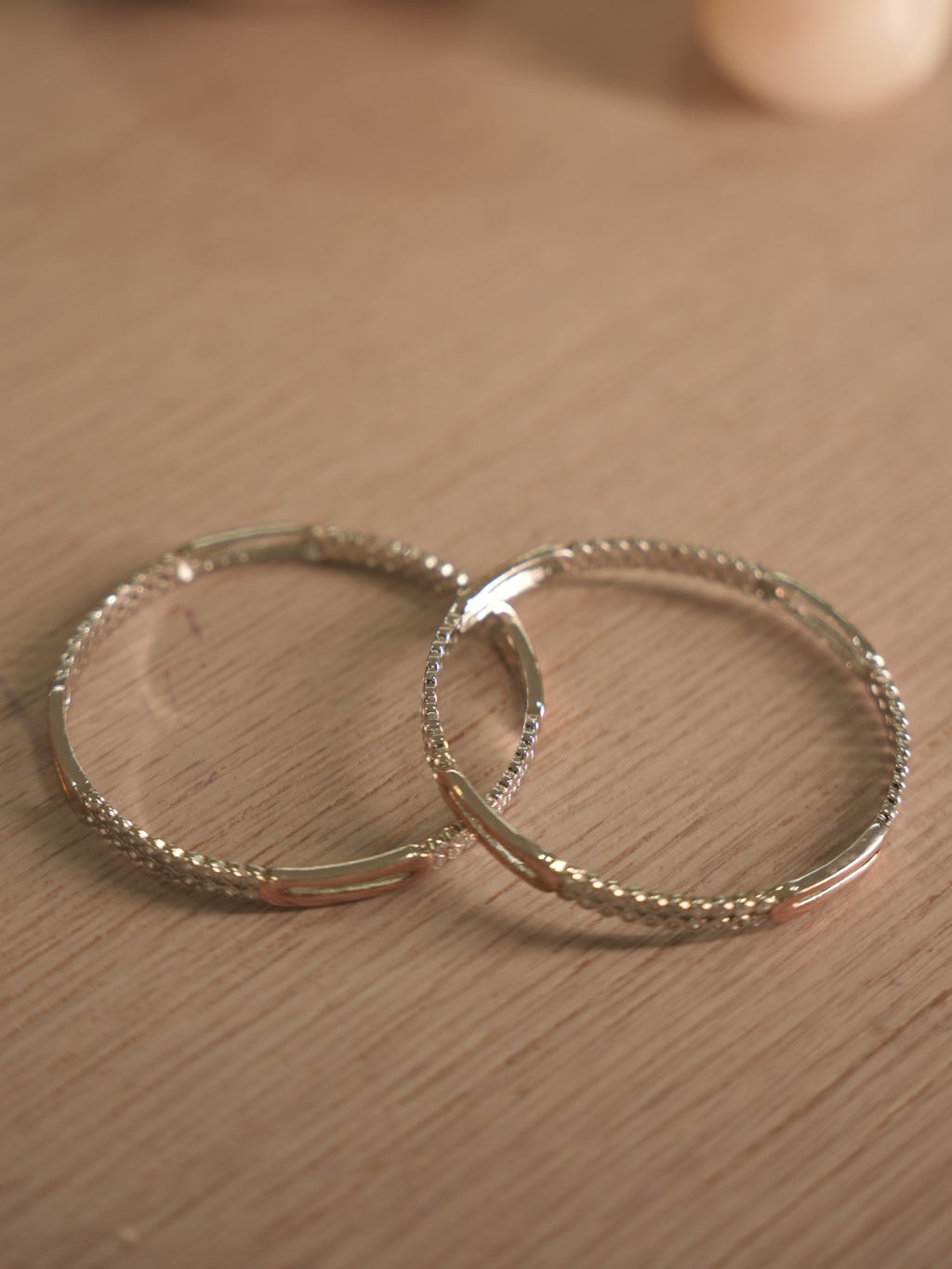 Side view of the American Diamond bangles, showing the bezel walls and the polished rose-tone stations.