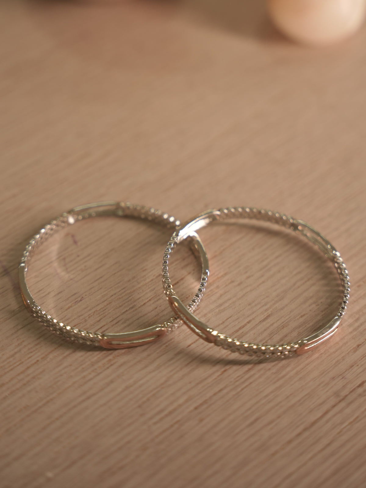 Side view of the American Diamond bangles, showing the bezel walls and the polished rose-tone stations.