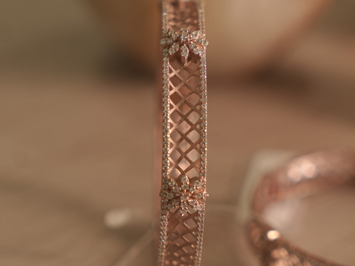 Close view of the rose-tone bangle, showing the satin lattice framed by pave set American Diamonds and a floral cluster.
