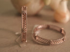 One rose-tone bangle standing and one lying flat, showing the width of the band and the stone set edges.