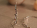 Slim two-tone sterling silver bangle standing upright, showing forked links meeting at polished bead nodes.
