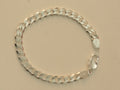 Sterling silver flat curb chain bracelet laid in a circle with the lobster clasp open.