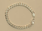Sterling silver flat curb chain bracelet laid in a circle with the lobster clasp open.