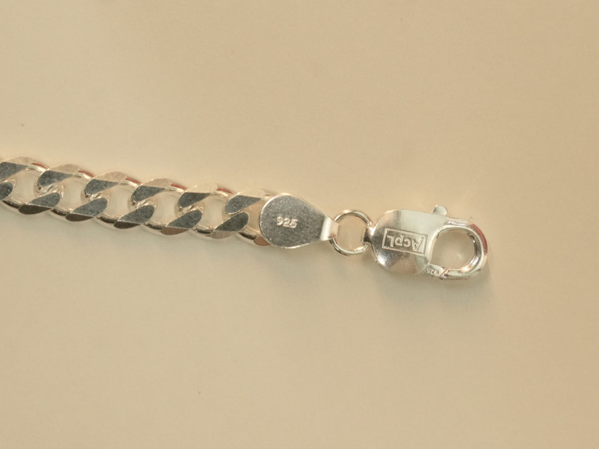 Close view of the lobster clasp and the end tab stamped 925 on the curb chain bracelet.
