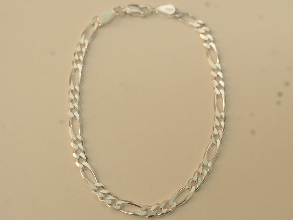 Sterling silver figaro chain bracelet laid in an oval, closed at the lobster clasp.
