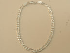 Sterling silver figaro chain bracelet laid in an oval, closed at the lobster clasp.