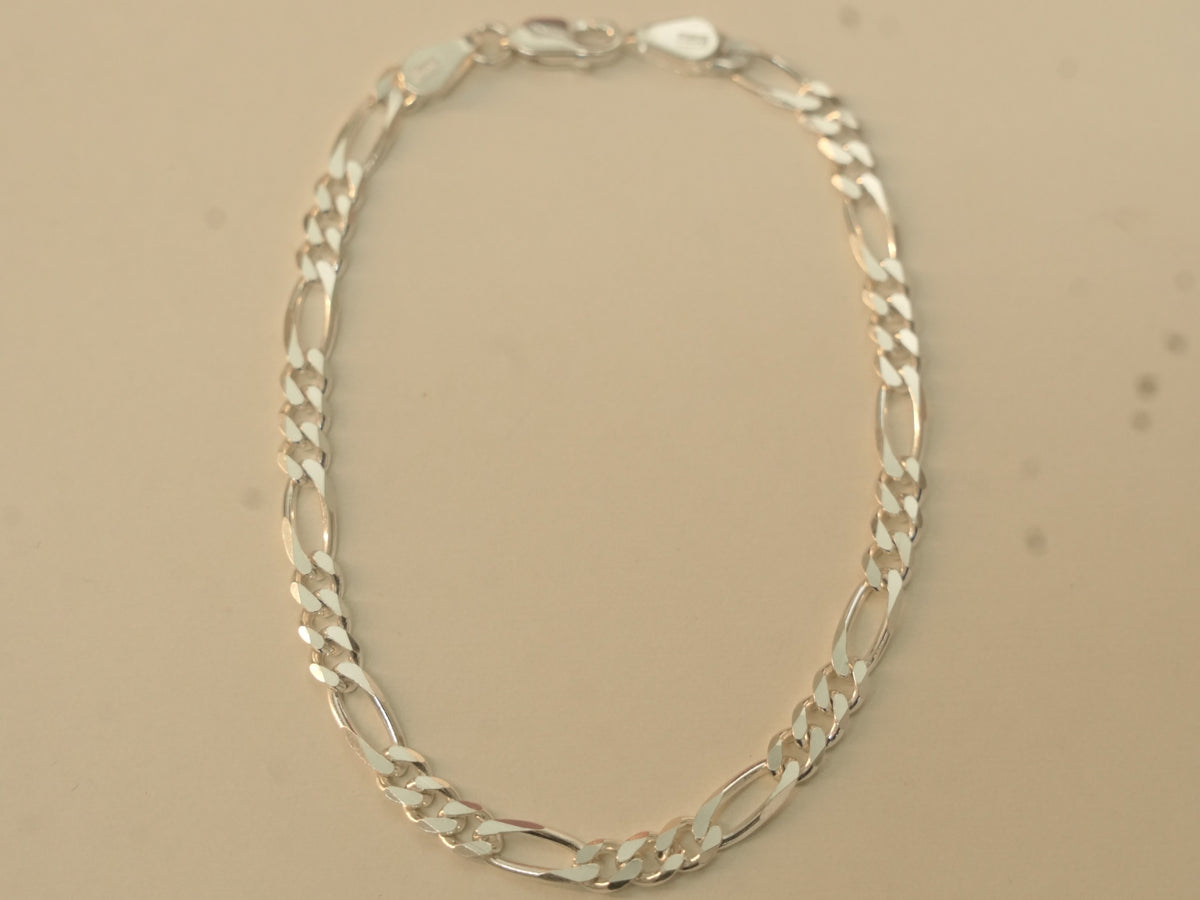 Sterling silver figaro chain bracelet laid in an oval, closed at the lobster clasp.