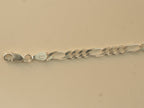 Close view of the lobster clasp and the stamped end tab on the figaro chain bracelet.